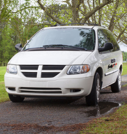 White mini van on a gravel driveway after a rain storm